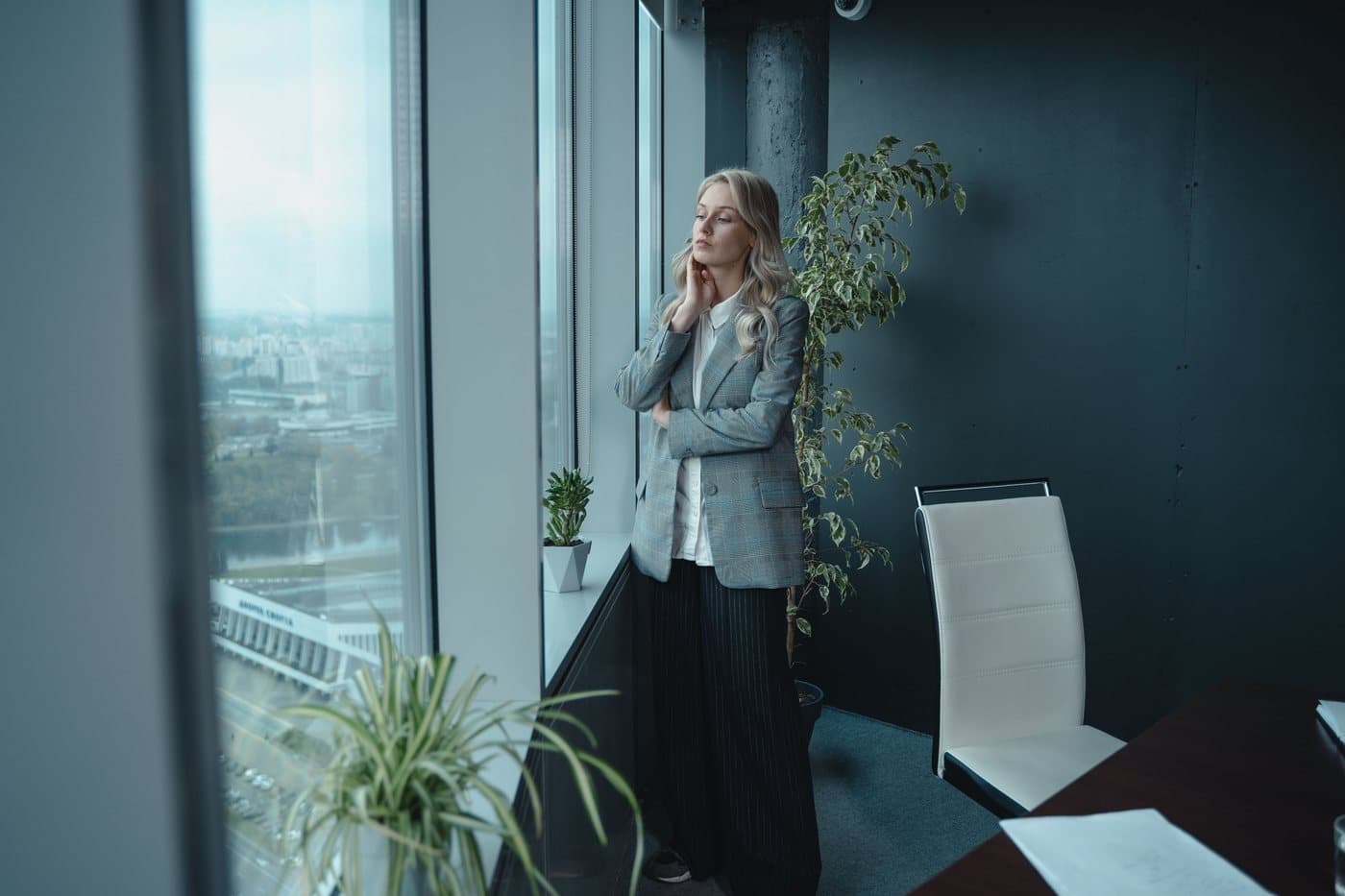 A professional reflecting on their career direction beside an office window